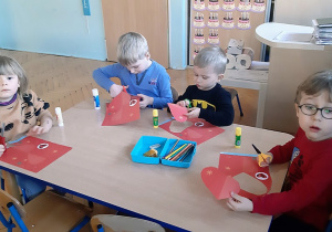 Dzieci wykonują walentynkowe serduszka z papieru.